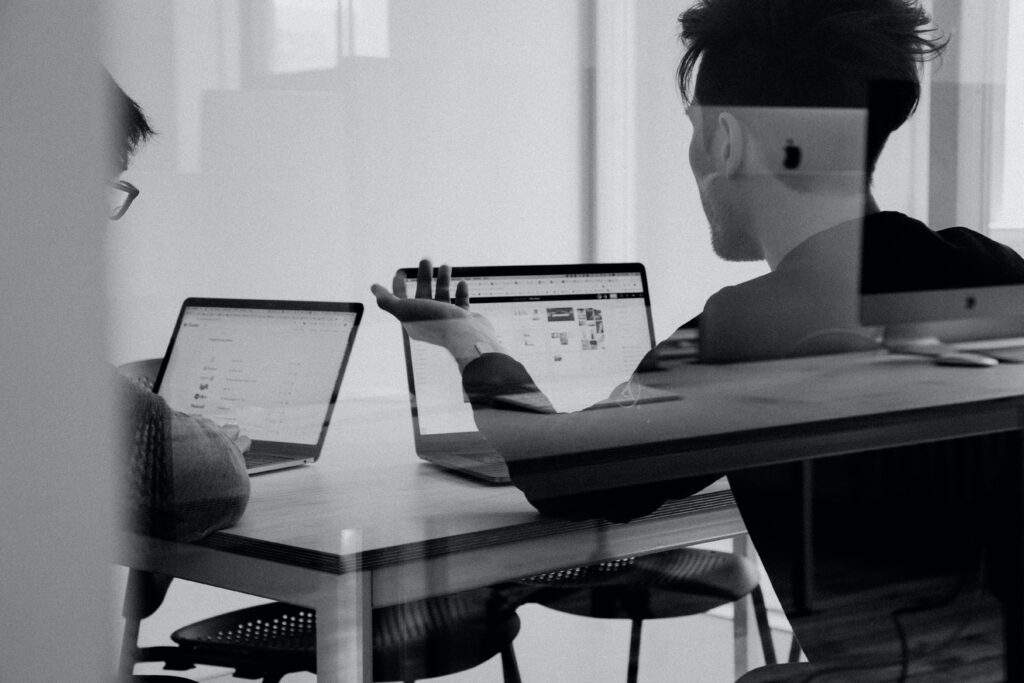 2 people talking in front of their laptops